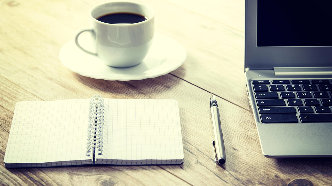 Cuaderno y taza de café sobre una mesa de madera