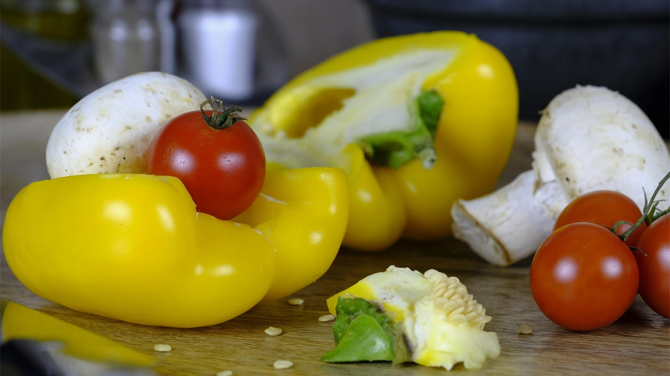 Pimientos amarillos y tomates cherry sobre una tabla de madera