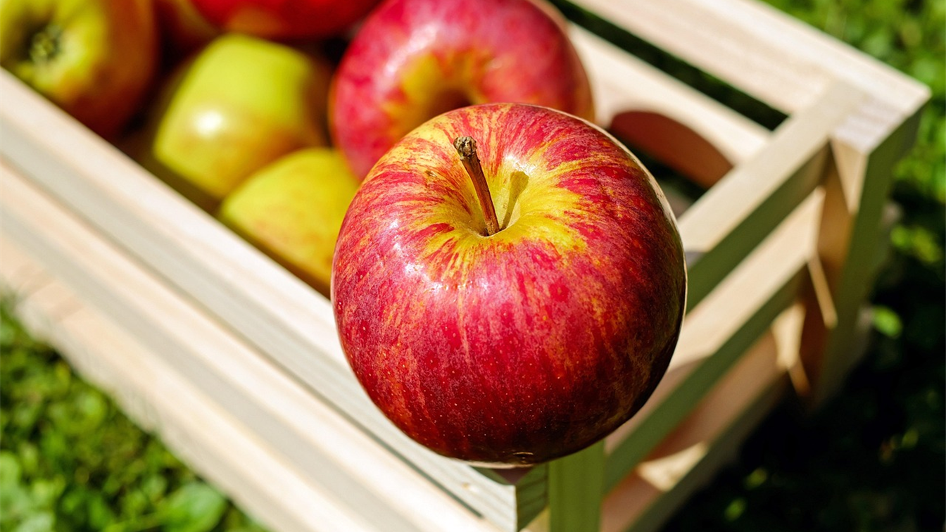 Manzanas rojas y verdes en una caja de madera al aire libre
