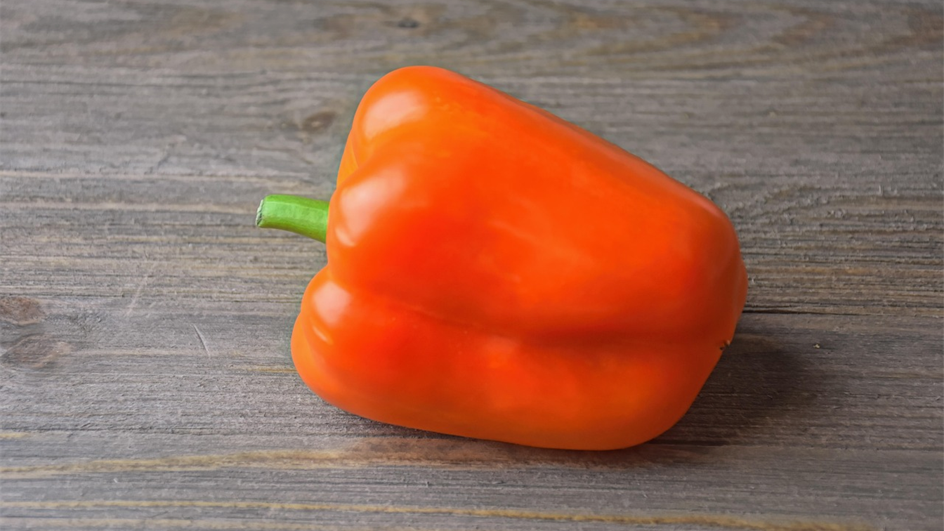 Pimiento naranja sobre una mesa de madera