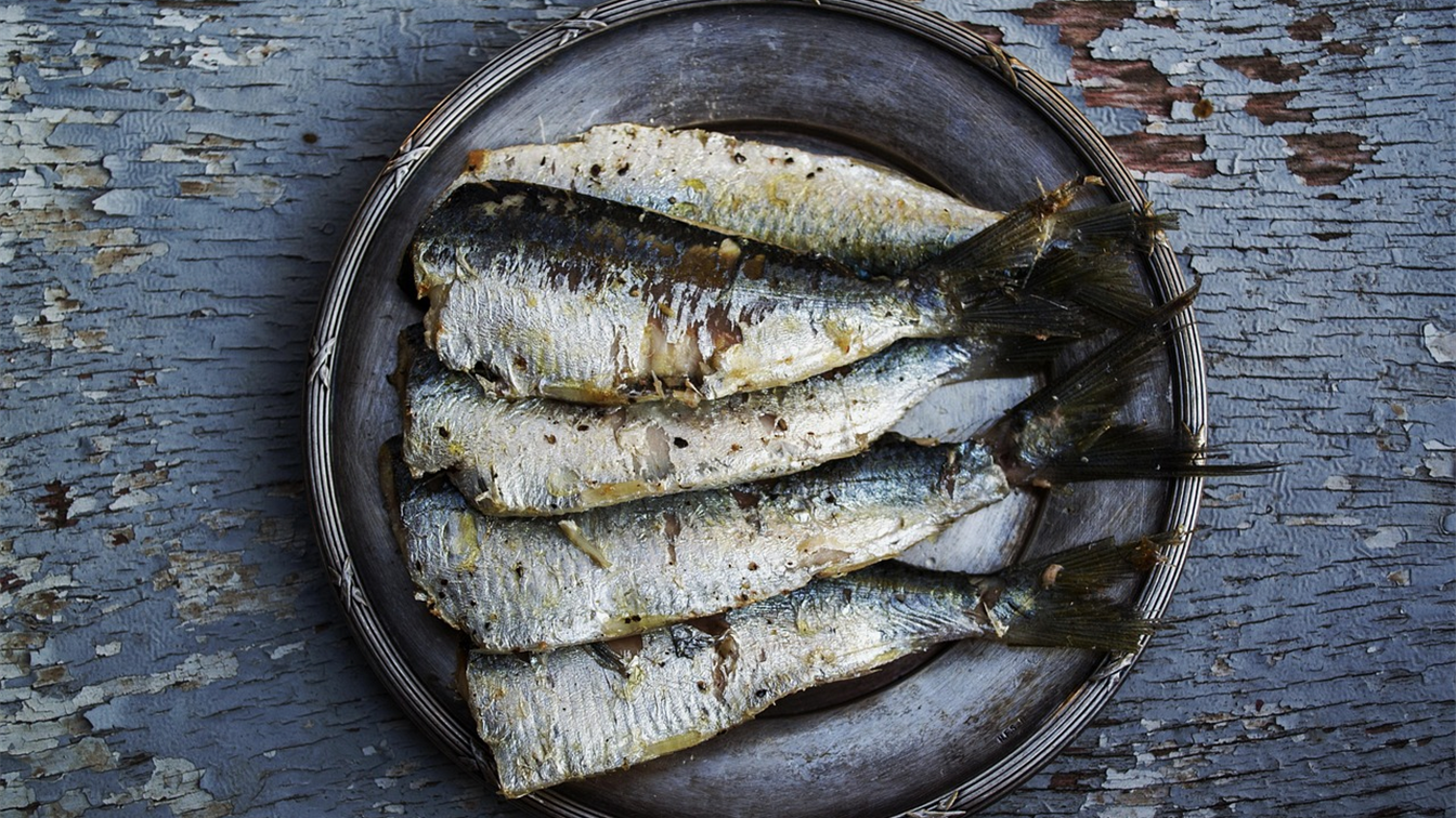 Sardinas asadas en un plato sobre una mesa de madera envejecida